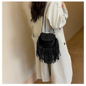 Detail of black suede saddle bag featuring long fringe decor and woven stitching details