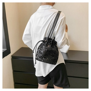 Détail du sac seau à paillettes noires avec cordon de serrage sur l'épaule du modèle