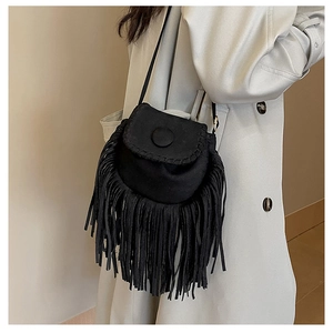 Detail of black suede crossbody bag featuring long bohemian tassels and woven edge stitching