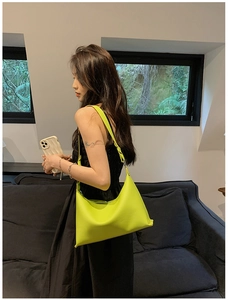 Dettaglio della borsa a secchiello verde neon minimalista con trama in pelle martellata