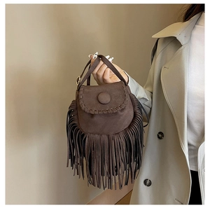 Detailed macro view of dark brown suede saddle bag featuring long fringe and stitching