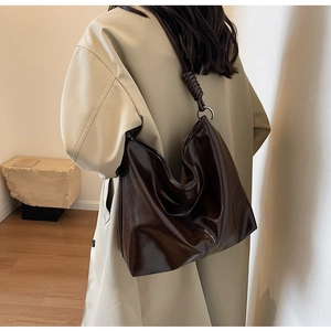 Detailed view of dark brown faux leather shoulder bag with woven knot strap and silver ring