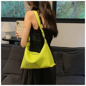 Vista dettagliata della borsa a secchiello verde neon con tracolla intrecciata dal design unico