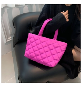 Detail of hot pink quilted puffer tote bag featuring vibrant diamond stitching and handle