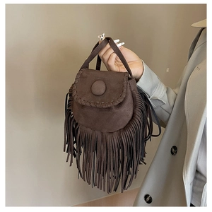 Detail of dark brown suede handbag with long tassels and thick stitching on saddle flap