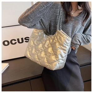 Close-up of silver quilted tote bag with large diamond stitching and metal chain strap