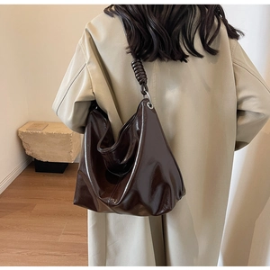 Close-up of a large chocolate brown tote bag with twisted strap and metallic finish