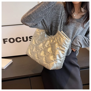 Detailed view of metallic silver quilted tote bag with diamond stitching and chain strap