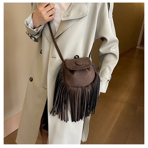 Detailed close-up of dark brown suede saddle bag with fringe tassels and woven edges