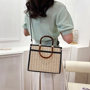 Handmade straw tote bag with black leather trim and brown rounded handles for beach holidays