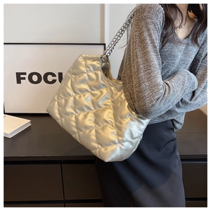 Detail view of silver quilted tote bag with metallic texture and chain strap on shoulder