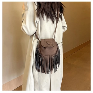 Detail of vintage brown suede crossbody bag with long fringes and circular flap design
