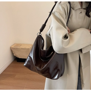 Detail view of dark brown glossy leather hobo bag with unique spiral shoulder strap detail