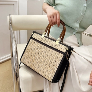 Handwoven straw tote bag with amber acrylic handles and black leather trim accents
