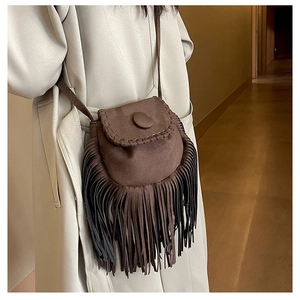 Brown suede tassel saddle bag worn by a model in a stylish long trench coat