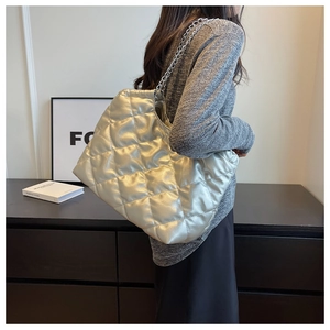 Silver quilted tote bag with chain strap shown on shoulder for capacity and style
