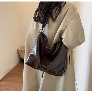 Detail of dark brown tote bag featuring glossy leather and a spiral textured strap design
