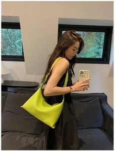 Dettaglio della borsa a mezzaluna verde lime in morbida pelle su vestito nero