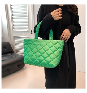 Detail of bright green quilted puffer tote bag with diamond pattern and soft handle