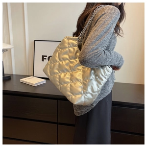 Detailed view of silver quilted chain shoulder bag with metallic finish on a model