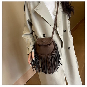 Detail of dark brown faux suede crossbody bag with long fringes and woven stitching details