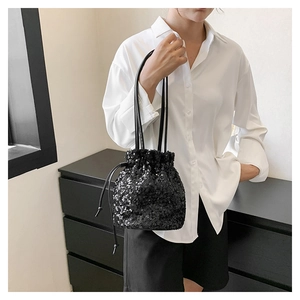 Détail du sac seau à paillettes noires avec cordon porté avec une chemise blanche