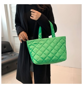 Detail of a bright green quilted tote bag with large diamond patterns and soft padded handles