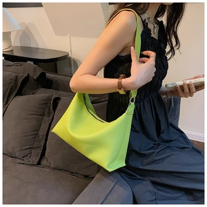 Borsa hobo verde lime con motivo litchi indossata a spalla in un interno elegante