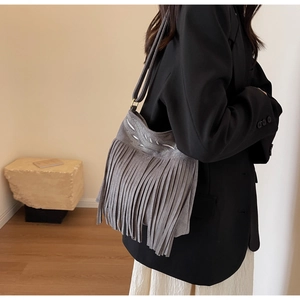 Détail du sac à bandoulière gris en daim avec broderie de feuilles et pompons