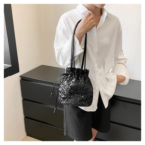 Gros plan du sac seau à paillettes noires avec cordon de serrage et poignée en cuir