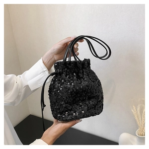 Détail d'un élégant sac seau à paillettes noires avec cordon tenu à la main avec soin