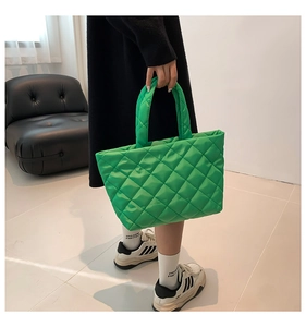 Quilted green puffer tote bag shown as a crossbody styling on a casual model outfit