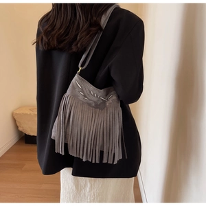Détail du sac seau bohème gris avec broderie rétro et longues franges en daim