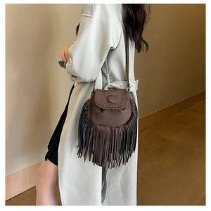 Detailed view of bohemian dark brown suede saddle bag with long fringes and woven edges
