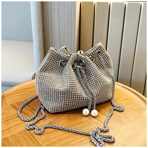 Détail d'un sac seau argenté avec strass, cordon de serrage et breloques perles