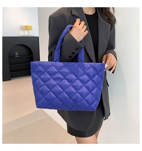 Deep purple quilted tote bag with diamond pattern shown on a stylish model