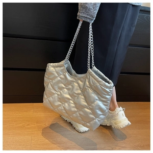 Detail of silver quilted tote bag with metallic finish and dual chain shoulder straps