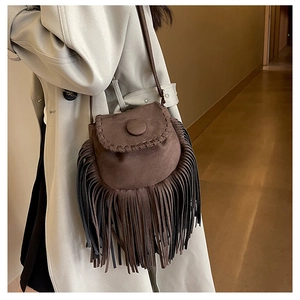 Detailed close-up of brown suede saddle bag featuring bohemian fringe and decorative stitching