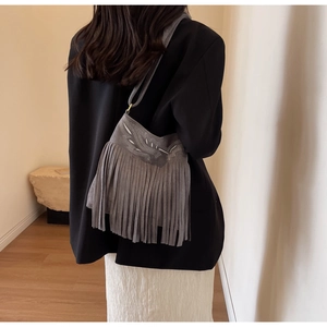 Détail du sac seau en daim gris avec broderie ethnique et longues franges rétro