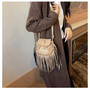 Detail of bohemian suede saddle bag with fringe tassels and woven stitching accents