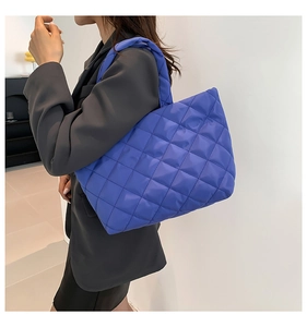 Royal blue quilted tote bag with diamond pattern shown as a large shoulder bag on model