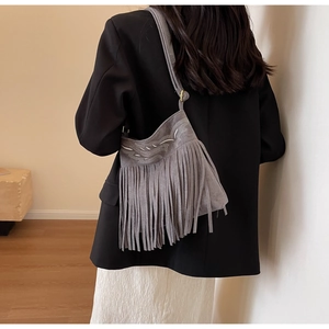 Détail du sac seau en daim gris avec broderie ethnique et accents de glands bohèmes