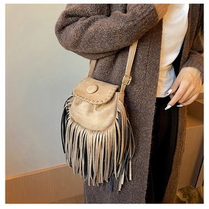 Detail of bohemian suede crossbody bag showing intricate fringe and decorative round buckle