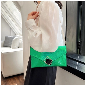 Elegante pochette a busta verde brillante con trama a pietra e catena dorata su modella
