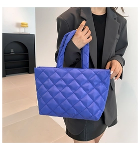 Detail of purple quilted puffer tote bag with classic diamond stitching and lightweight texture