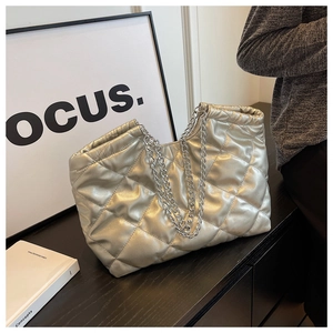 Macro detail of champagne gold quilted tote with silver chain and drawstring closure