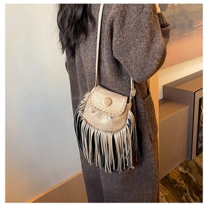 Detail view of suede saddle bag with woven trim and decorative two-tone tassels