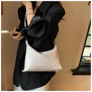 Dettaglio ravvicinato di una borsa a secchiello bianca testurizzata con blazer nero
