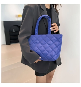 Quilted blue tote bag with diamond pattern shown on a model in a modern office setting