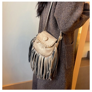 Detail shot of the suede crossbody saddle bag with flowing fringe and textured braid trim